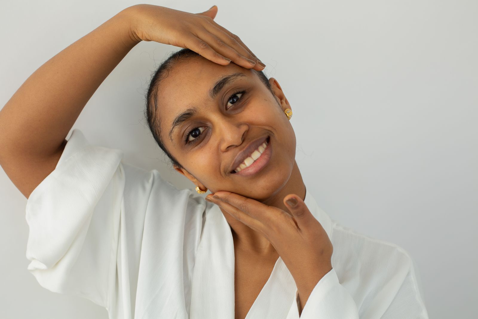 Smiling woman with smooth, healthy skin, gently touching her face